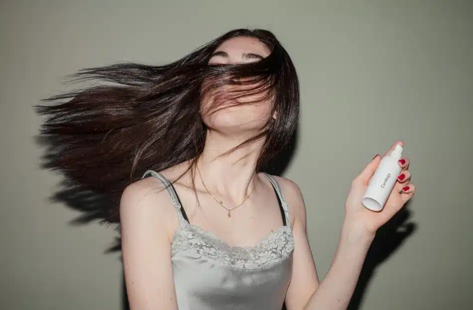 une femme mettant un spray dans ses cheveux